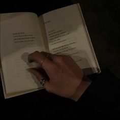 a person is holding an open book in their left hand and touching it with the other hand