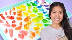 a girl is holding up a tray with gummy bears on it and there are other gummy bears in the tray