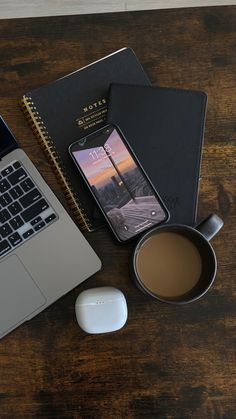 an open laptop computer sitting on top of a wooden desk next to a cup of coffee