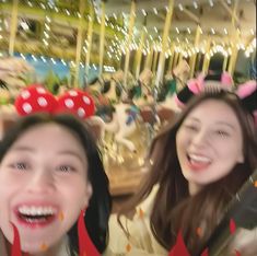 two girls wearing minnie mouse ears are smiling at the camera