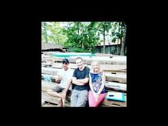 three people are sitting on some wooden planks