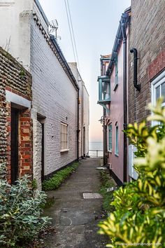 an alley way between two brick buildings with the ocean in the backgroung