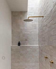 a bathroom with white tile and gold fixtures on the shower head is shown in this image