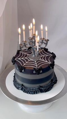 a spider web cake with candles in it on a white tablecloth covered platter