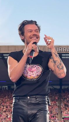 a man holding a microphone in front of a crowd at a sporting event with tattoos on his arms