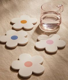 four flower shaped coasters next to a glass of water