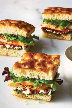 four sandwiches with different toppings on a white plate next to a bowl of salsa