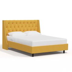 a bed with an upholstered headboard and foot board in yellow linens