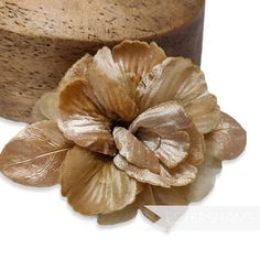 a gold flower is sitting on top of a wooden hat box and it's brown fabric