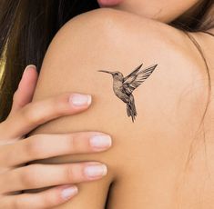 a woman's arm with a tattoo on it that has a hummingbird flying over her shoulder