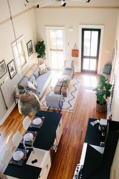 an overhead view of a living room and dining room with wood floors, white walls, and black furniture