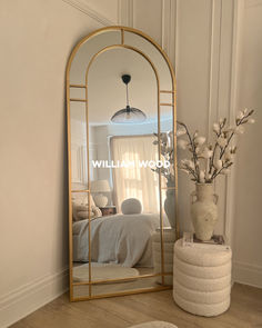 a mirror sitting on top of a wooden floor next to a vase filled with flowers