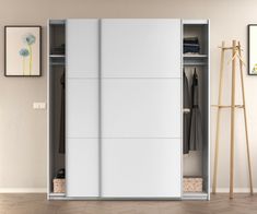 an open white closet with clothes hanging on the wall and coat rack in front of it