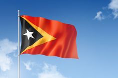 a flag flying in the wind on a clear day with blue sky and white clouds