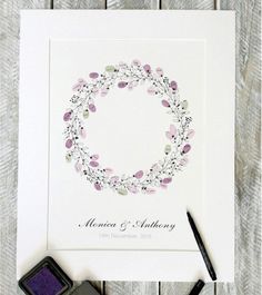 a wedding card with a flower wreath on it next to a stamper and ink pen