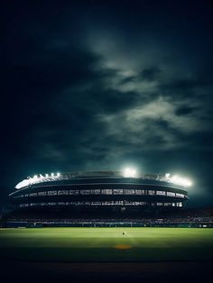 an empty stadium at night with the lights on and dark clouds in the sky above