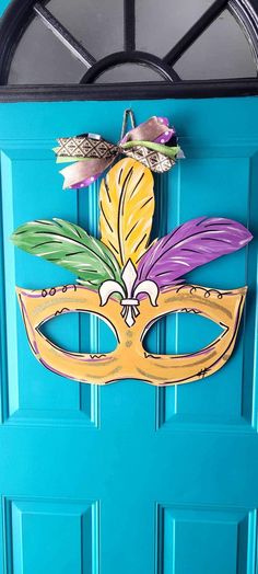 a blue door with a mask painted on it's side and flowers in the middle