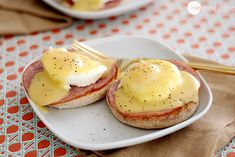 two plates with eggs, ham and cheese on them sitting on a table next to a fork