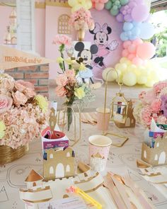 a table topped with lots of pink flowers and paper crafts on top of a white table cloth