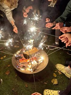 several people standing around a cake with sparklers on it