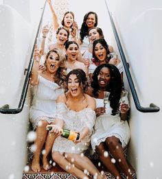 a group of women sitting on top of an escalator with champagne bottles in their hands