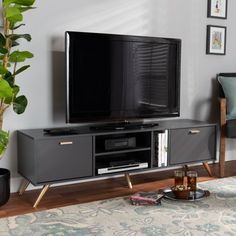 a flat screen tv sitting on top of a wooden entertainment center next to a potted plant