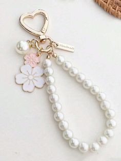 the key chain is decorated with flowers and pearls on it's end, along with a heart shaped charm