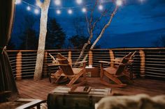 a deck with wooden chairs and string lights