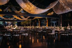 a banquet hall with tables and chairs covered in white draping at night time