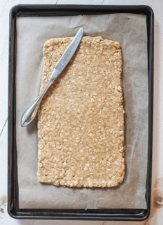 a square cookie on a baking sheet with a knife next to it, ready to be baked