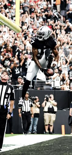 a football player jumping into the air to catch a ball in front of an audience