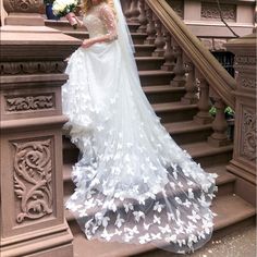 a woman in a wedding dress is standing on the stairs with her veil pulled back