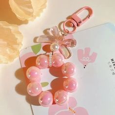 a pink bracelet with pearls and a bow on it sitting next to a white card