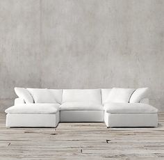 a white couch sitting on top of a wooden floor next to a cement wall with no one in it