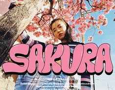 a woman standing next to a tree with the word sakra written in pink on it