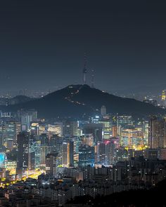 cityscape at night with mountains in the background and buildings lit up on both sides