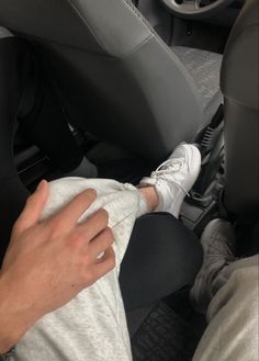 a person sitting in the passenger seat of a car with their foot on a cloth