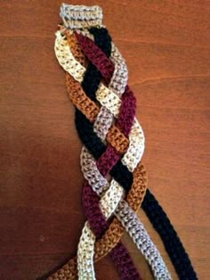 a multicolored crocheted tie sitting on top of a wooden table