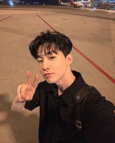 a young man making the peace sign on an airport tarmac