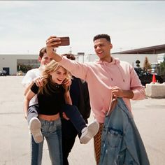 a group of people standing around each other taking a selfie with a cell phone