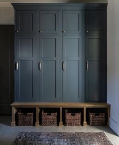 a room with some blue cabinets and baskets on the floor in front of an area rug