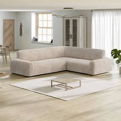 a living room with a sectional couch and coffee table on the floor in front of a window