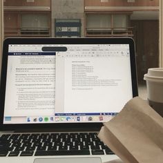 an open laptop computer sitting on top of a desk next to a cup of coffee