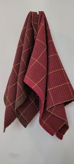 a red and brown checkered towel hanging on a hook in front of a white wall