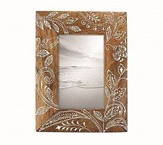 a wooden frame with an intricate design on the front and sides, along with a beach scene in the background