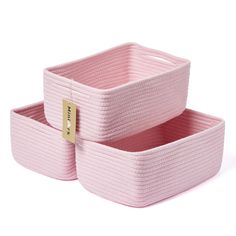 two pink storage baskets sitting next to each other on a white surface with a gold tag