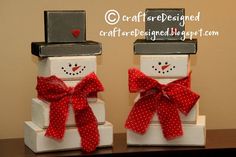 two snowmen with red bows on their heads are sitting on top of each other