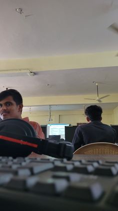 two men sitting in front of a computer keyboard