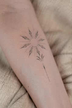 a woman's arm with a small flower tattoo on the left side of her arm