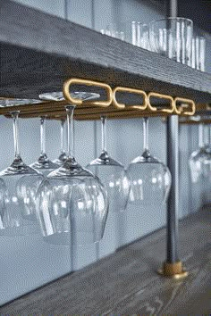 several wine glasses are hanging on the wall next to a rack with gold bar handles